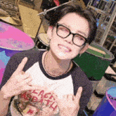 a young man wearing glasses and a black sabbath shirt giving the middle finger