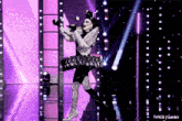 a woman in a clown costume is on a stage with purple lights behind her