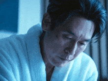 a man wearing a bathrobe looks down at something