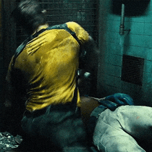 a man in a yellow shirt is kneeling down next to a man laying on the ground