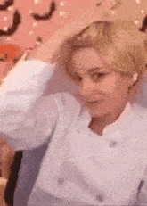 a woman in a white jacket is holding her hair in her hands .