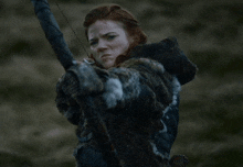 a woman holding a bow and arrow in a field