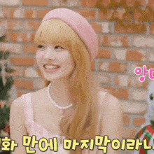 a woman wearing a pink beret and a pearl necklace smiles