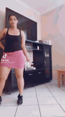 a woman in a pink skirt is dancing in a living room .