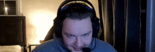 a man wearing headphones and a microphone is sitting in front of a computer screen