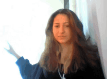 a woman with long hair is standing in front of a window