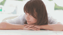 a woman rests her head on her hands and looks out a window