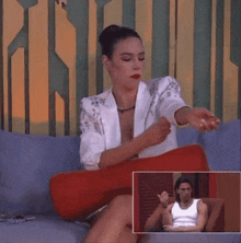 a woman is sitting on a couch with her eyes closed and a picture of a man in a white tank top behind her