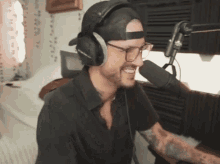 a man wearing headphones and a hat is smiling into a microphone .