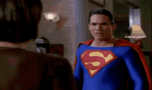 a man in a superman costume is standing next to another man .