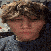 a close up of a person 's face in a blue sweater