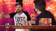 a man wearing a shirt that says like boy is talking to another man
