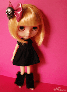 a doll wearing a black dress with a pink bow and a skull on her hair