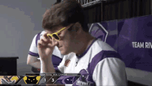 a man wearing sunglasses is sitting in front of a screen that says team rival
