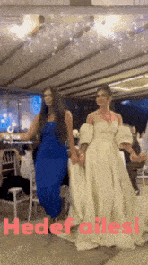 two women in dresses are dancing in a room with the words hedef ailesi on the bottom .