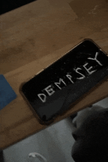 a broken cell phone with the word demsey written on it