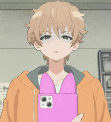 a boy in an orange hoodie is holding a pink phone with cat ears on it