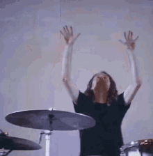 a man in a black shirt is playing a drum set