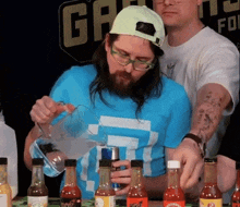 a man in a blue shirt is pouring something into a glass