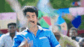 a man in a blue shirt with a mustache is dancing