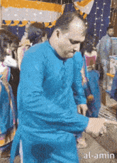 a man in a blue shirt is dancing in front of a crowd with the words al-amin written below him