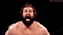 a man with a beard is screaming with his mouth open in a dark room .
