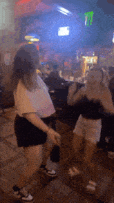 two women are dancing in a bar in front of a jack daniel 's sign .