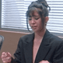 a woman in a suit is sitting at a table in front of a window .
