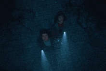a couple of people standing in a dark room with flashlights