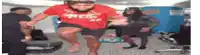 a man in a red shirt is jumping in the air in a gym while other people watch .