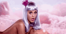 a naked woman in a wig is laying on her stomach in a cloud .