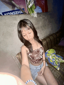 a young girl sits on a couch in front of a sign that says vonserah