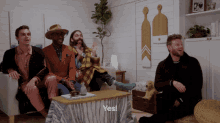 a group of men are sitting around a table and one of them is saying " yes "