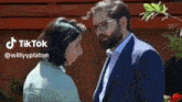 a man in a suit and glasses is kissing a woman in a green shirt .