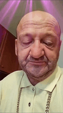 a bald man with a beard is wearing a chain around his neck .