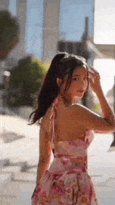 a young woman in a pink dress is standing on a sidewalk .