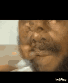 a close up of an older man 's face with a beard .