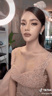 a woman in a wedding dress is getting her makeup done in front of a mirror .