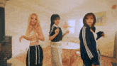 three women are dancing in a living room with a table