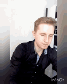 a man in a black shirt is sitting at a table with his eyes closed and the words inshot on the bottom