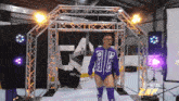 a wrestler wearing a purple shirt with the letter e on it