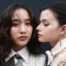 two women standing next to each other with one wearing a white shirt and tie