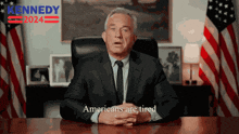 a man in a suit and tie is sitting at a desk in front of american flags and says americans are tired