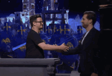 a man in a black shirt with a picture of a man on it shakes hands with another man