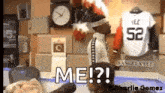 a man is standing in front of a clock and a jersey that says ' me ? ' on it .