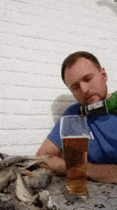 a man sitting at a table with a bottle of beer on his head and a glass of beer