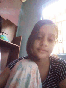 a woman in a black and white striped shirt is looking down at the camera