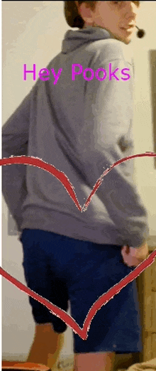 a man wearing a grey hoodie and blue shorts is standing in front of a heart that says hey pooks on it