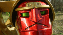 a red robot with green eyes and a gold helmet has a sad look on his face