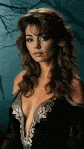 a woman in a black dress with a plunging neckline is looking at the camera